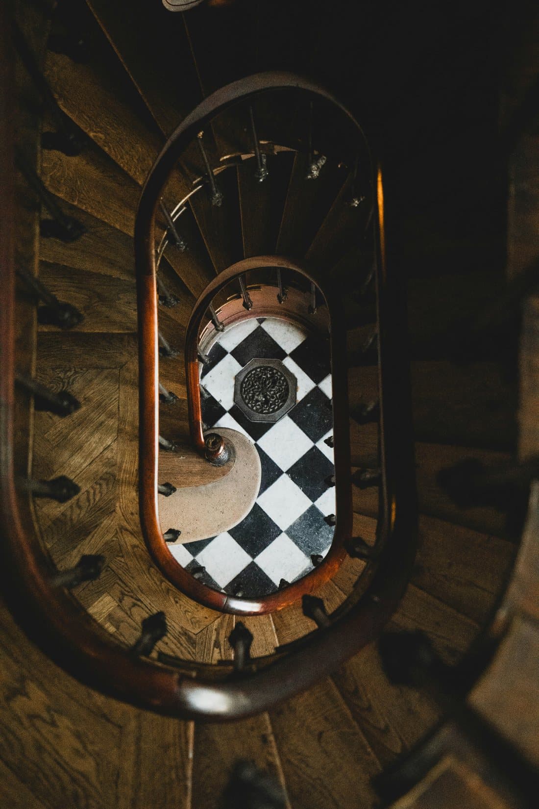A curved stair hall viewed from above, with a checkerboard floor below